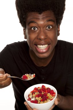 Beyaz bir arka plan üzerinde izole taze meyve ile tahıl yemek genç Afro Amerikan hipster yakışıklı olan. Sağlıklı gıda kavramı