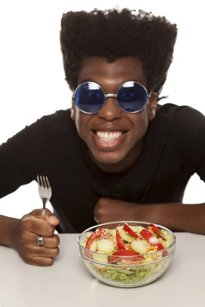 Young handsome Afro american guy eating salad isolated on a white background. healthy food concept
