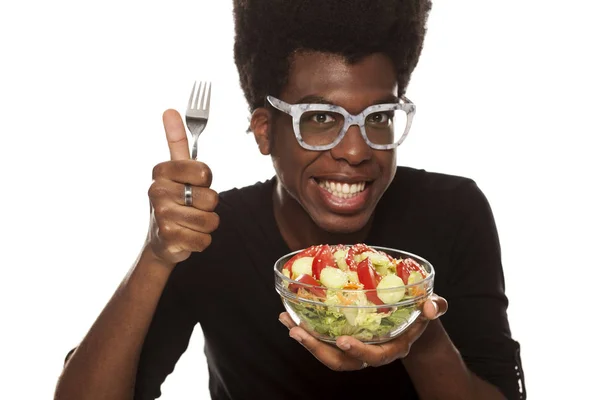 Young handsome Afro american guy eating salad isolated on a white background. healthy food concept