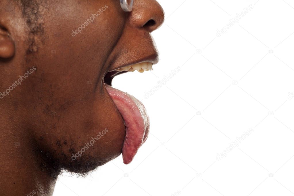 Close up profile view of a young black African american guy with his tongue sticking out on a white background