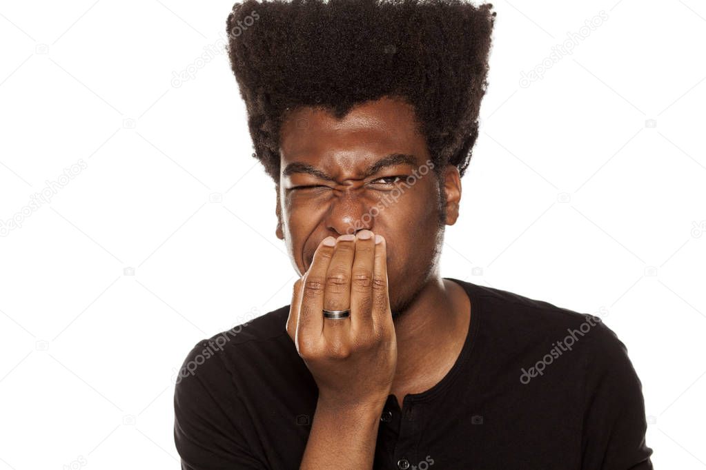 Portrait of a young African american modern man checking his breath on a white background