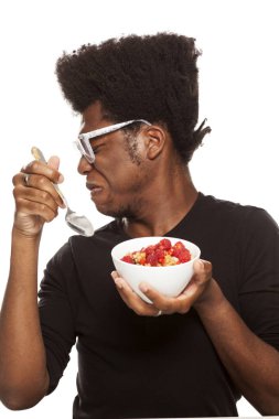 Beyaz bir arka plan üzerinde izole taze meyve ile tahıl yemek tiksinti genç Afro Amerikan hipster yakışıklı olan. Sağlıklı gıda kavramı