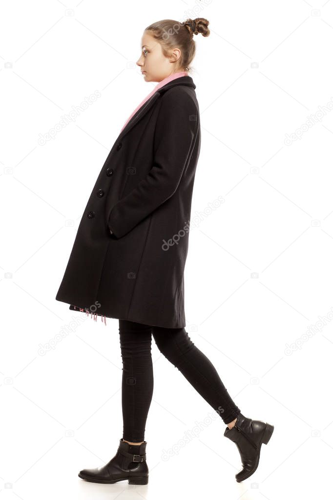 Profile view of a young girl in winter clothes posing on a white background