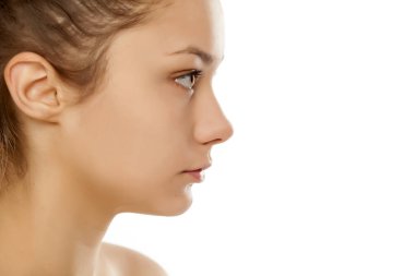 Beyaz bir arka plan üzerinde makyaj olmadan bir genç kızın profil görünümü