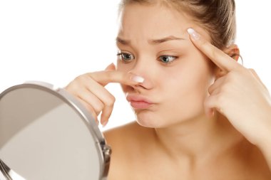 Genç kız beyaz arka planı yansıtmadaki yüzüne kontrol