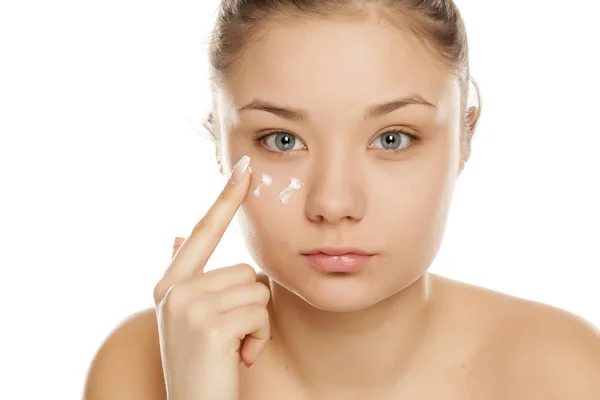 Chica Joven Aplicando Crema Facial Sobre Fondo Blanco —  Fotos de Stock