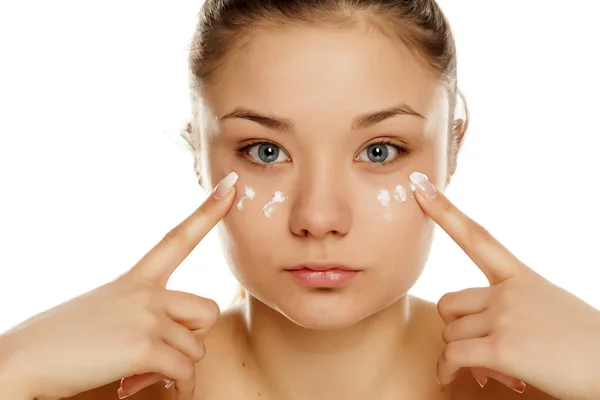 Chica Joven Aplicando Crema Facial Sobre Fondo Blanco — Foto de Stock