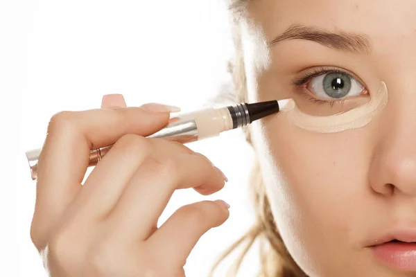 Chica Joven Aplicando Corrector Sobre Fondo Blanco —  Fotos de Stock