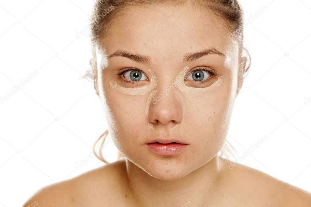 Young girl with concealer on a white background