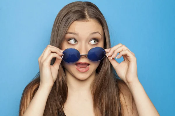 Junges Lustiges Mädchen Mit Blauer Sonnenbrille Auf Blauem Hintergrund — Stockfoto