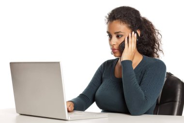 Güzel koyu tenli öğrenci telefonda konuşurken ve beyaz arka plan üzerinde dizüstü bilgisayar üzerinde çalışıyor