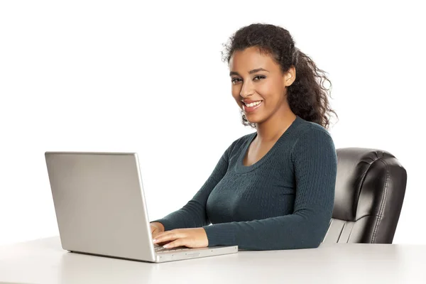 ノートパソコンを使用して美しい顔を持つ笑顔と肯定的な幸せな若いアフリカ系アメリカ人の女性 白い背景の机でプロジェクトを働く — ストック写真