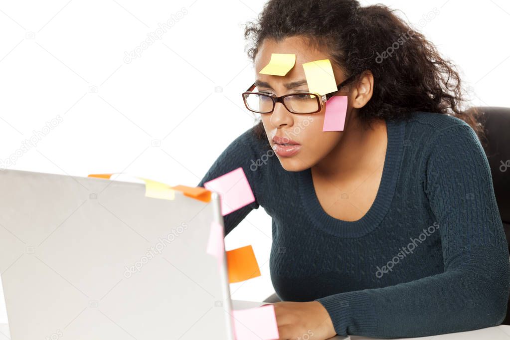 Confused young african woman with stickers on her head and comuter on white background