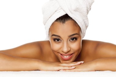 beyaz bir arka plan üzerinde yatan, başında havlu ile genç güzel koyu tenli kadının portresi