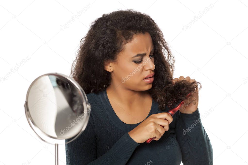 portrait of young dark-skinned woman with long hair combing problem on white background