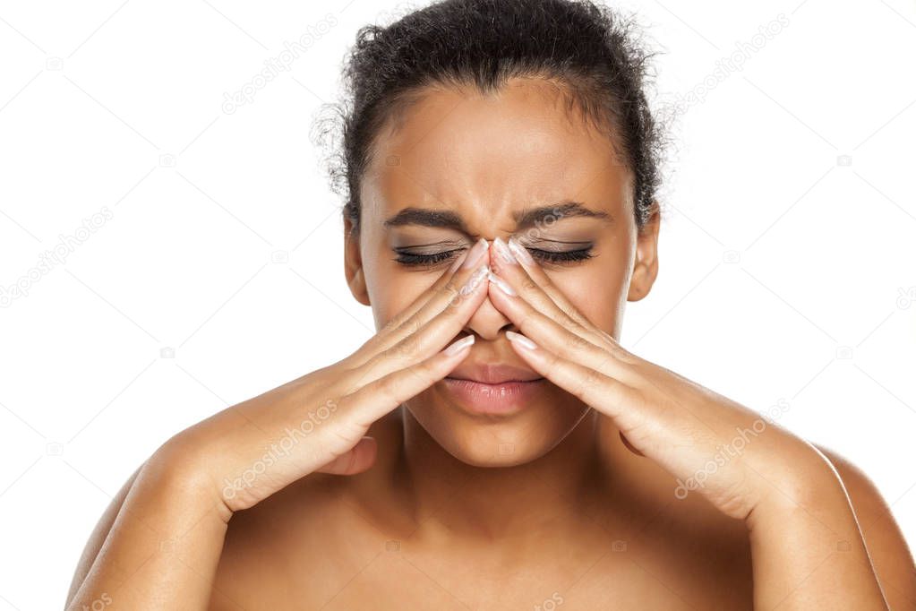 portrait of young dark-skinned woman with sinusitis on white background