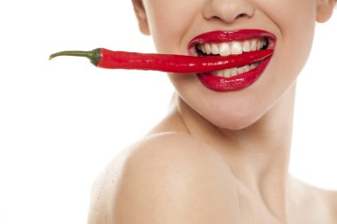 Genç seksi kadın beyaz arka plan üzerinde dişleri ile bir biber tutan