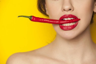 Genç seksi kadın beyaz arka plan üzerinde dişleri ile bir biber tutan