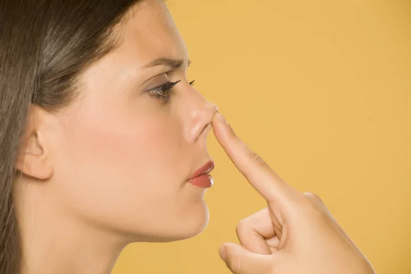 Mooie Jonge Vrouw Aanraken Haar Neus Met Haar Vinger Gele — Stockfoto