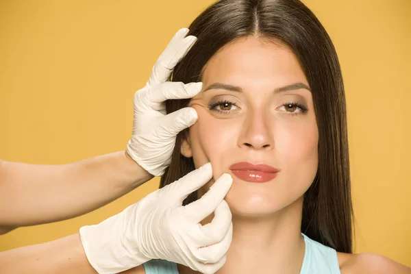 Ręce Lekarza Kontroli Wrincles Młodej Kobiety Żółtym Tle — Zdjęcie stockowe