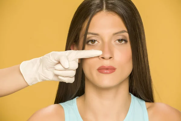 Ręce Lekarza Dotykając Nosa Młodej Kobiety Żółtym Tle — Zdjęcie stockowe