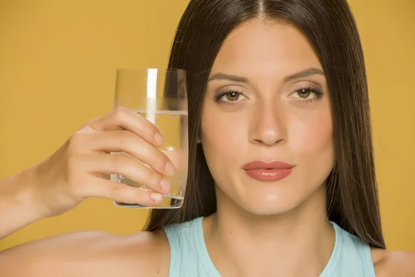 Mujer Joven Sosteniendo Vaso Agua Sobre Fondo Amarillo —  Fotos de Stock