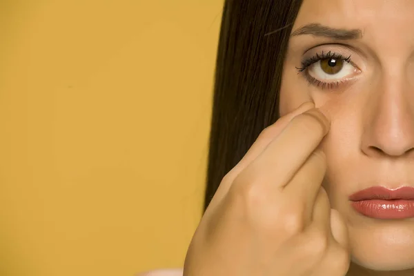 Jovem Mulher Triste Tocando Suas Pálpebras Baixas Fundo Amarelo — Fotografia de Stock