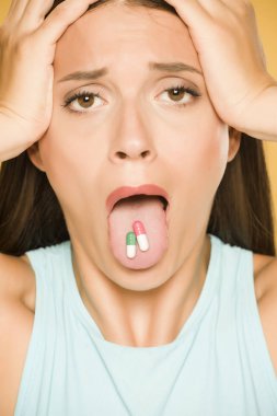 Mutsuz genç kadın dilinde kapsül tutan