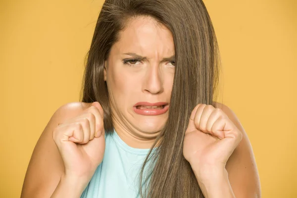 young disgusted woman on yellow background
