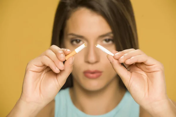 Mujer Joven Sosteniendo Cigarrillo Roto Sobre Fondo Amarillo —  Fotos de Stock