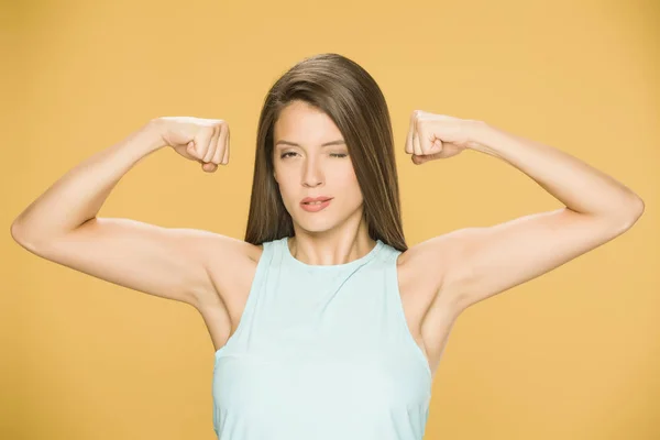 Young woman showing her hands on yellow background