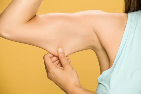 Jovem Mulher Beliscar Gordura Sua Mão Fundo Amarelo — Fotografia de Stock