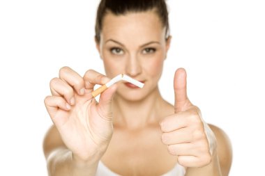 beyaz arka plan üzerinde kırık bir sigara tutan ve başparmak gösteren genç kadın