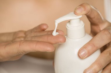 Pompa ile şişeden cilt kremi uygulayan kadın