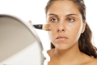 Genç ve güzel bir kadın fırçayla sıvı taban uyguladı.