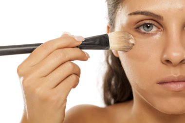 Genç ve güzel bir kadın fırçayla sıvı taban uyguladı.