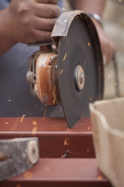 İşçi elektrikli testereyle metal bir boru kesiyor.