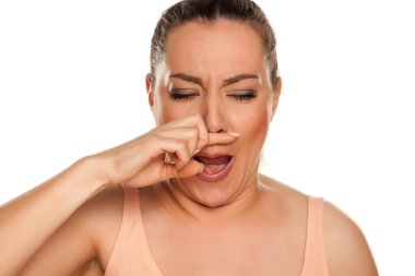 Genç bir kadının beyaz arka planda burnu kaşınıyor.