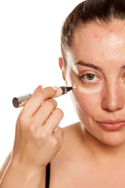 Young Woman Applying Concealer Her Eyes Brush White Background — Stock Photo, Image