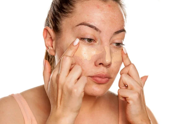 Young Woman Applying Concealer Her Eyes Her Fingers White Background — Stock Photo, Image