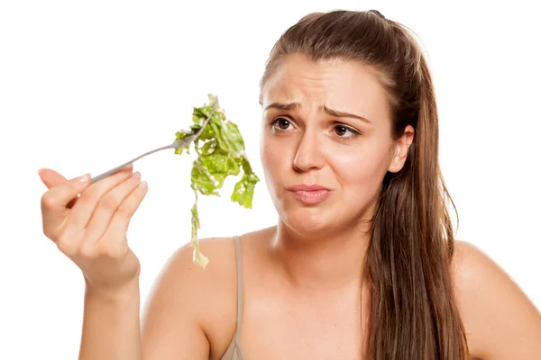 Joven Mujer Infeliz Sosteniendo Tenedor Con Lechuga Sobre Fondo Blanco — Foto de Stock