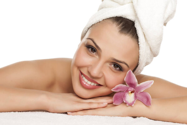 a pretty young woman lying with orchid on a white background