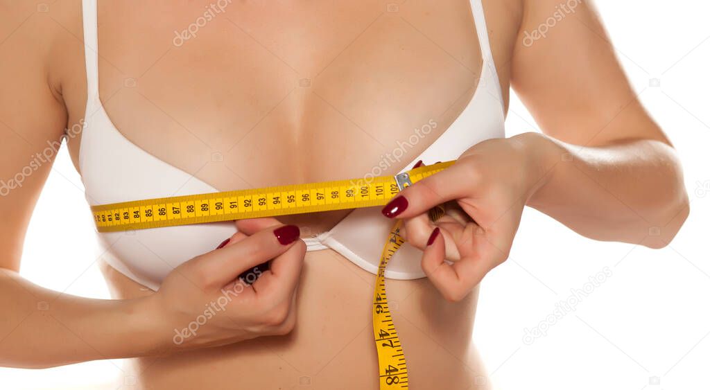 woman measures her breasts with a measuring tape