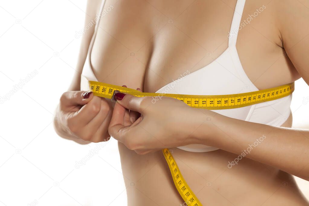 woman measures her breasts with a measuring tape
