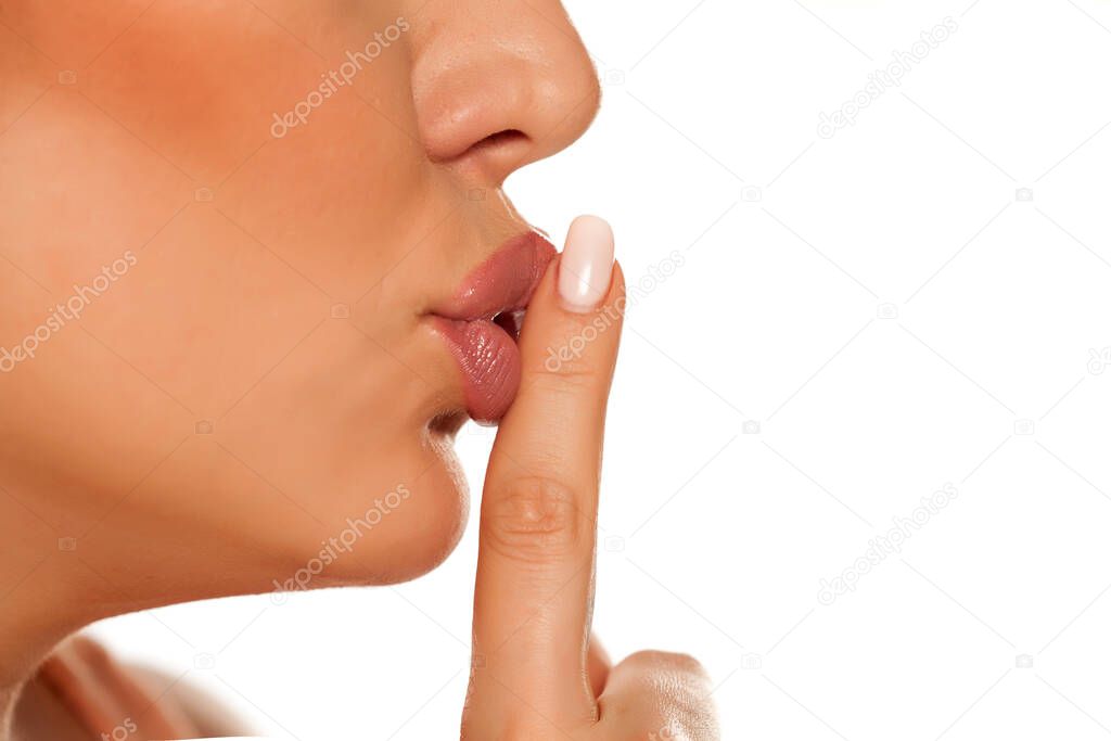 Profile of woman with index finger on her lips on white background