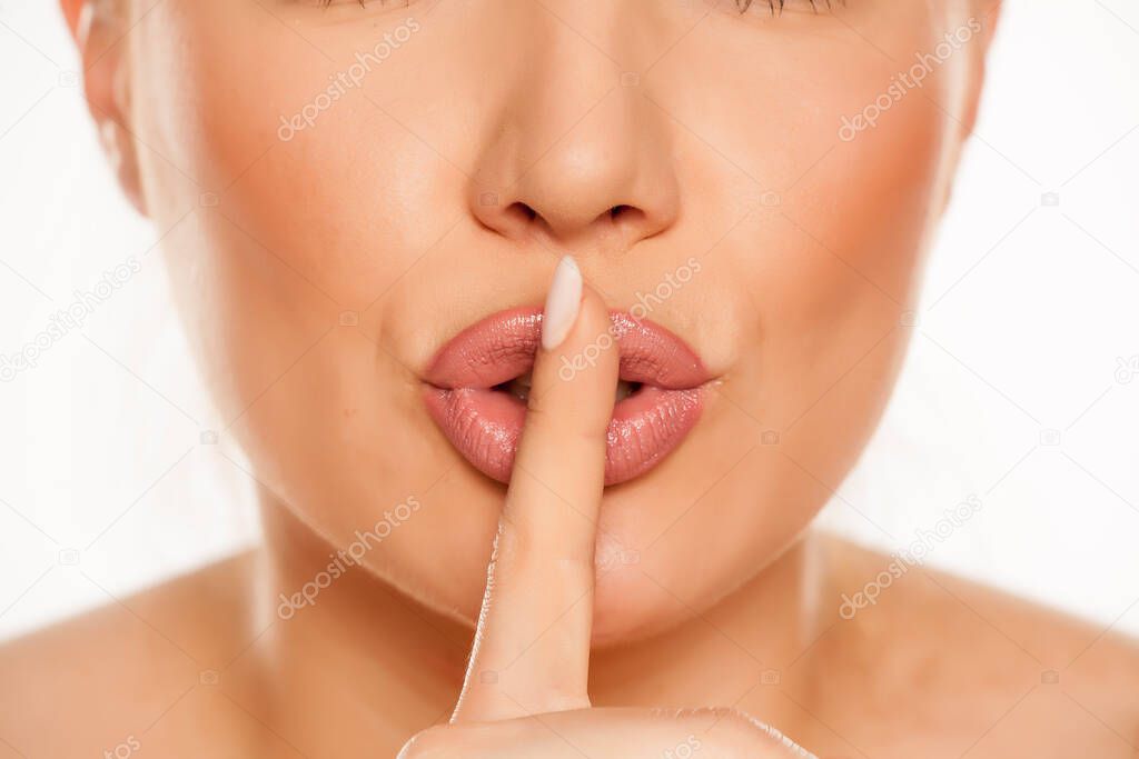 Portrait of woman with index finger on her lips on white background
