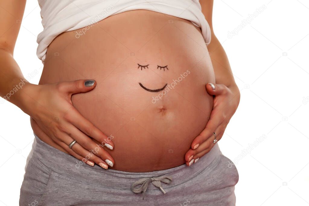 Pregnant woman posing with a smiley face on her stomach