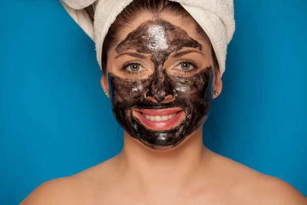 Młoda Uśmiechnięta Kobieta Ręcznikiem Głowie Pozująca Czarną Maską Twarzy — Zdjęcie stockowe