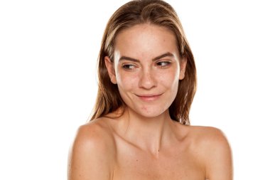 Beyaz arka planda makyajsız gülümseyen güzel bir kadının portresi.