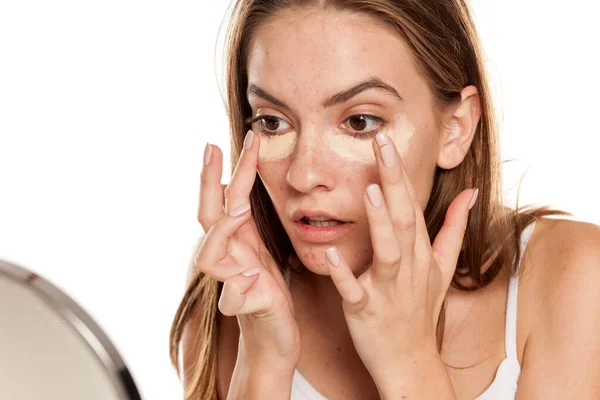 Jovem Menina Bonita Aplicando Corretor Com Dedos Sob Olhos Backgeound — Fotografia de Stock